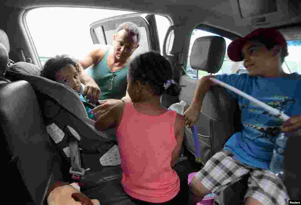 Estanislao Fabian straps Jaden Fabian (L), 1, into her car seat by as her family evacuates their home as Tropical Storm Isaac heads towards the Louisiana coast line in Oakville, Louisiana, August 28, 2012. 