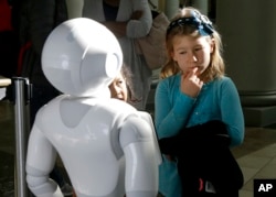 Emerson Hill, 6, seems a bit doubtful as she interacts with Pepper the robot at Westfield Mall in San Francisco, Dec. 22, 2016.