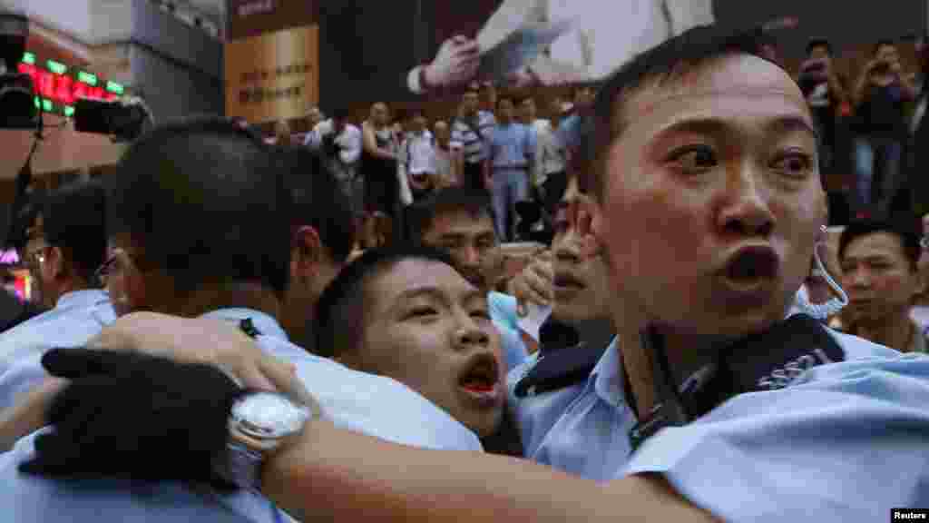 A pro-democracy protester, center, bleeds in the month as he is escorted by the police after being beaten by anti-Occupy Central protesters at Hong Kong's shopping Mongkok district, where a main road is occupied, Oct. 3, 2014. 