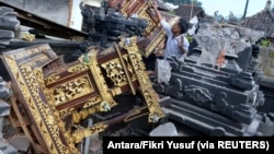 Seorang pria terlihat di antara bangunan pura yang rusak setelah gempa berkekuatan 4,8 melanda timur laut Bali, di Karangasem, Bali, 16 Oktober 2021, (Foto: Antara/Fikri Yusuf via REUTERS)