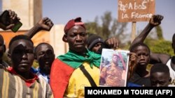 Des manifestants rassemblés à Ouagadougou pour montrer leur soutien aux militaires tiennent une photo du lieutenant-colonel Paul-Henri Sandaogo Damiba, chef de la mutinerie et du Mouvement patriotique pour la protection et la restauration (MPSR) le 25 janvier 2022.