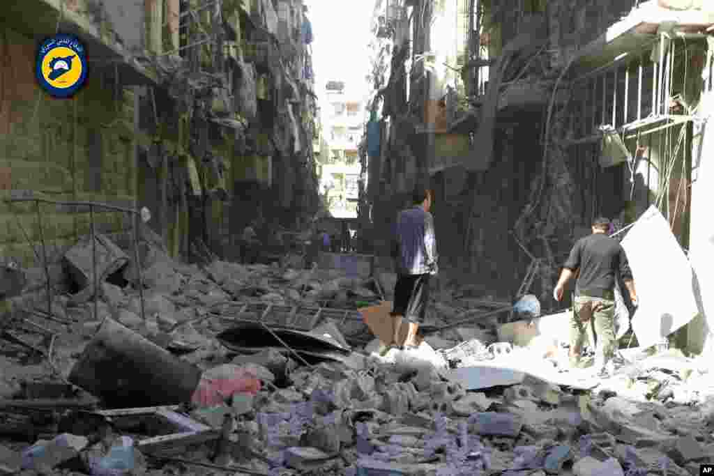 In this photo provided by the Syrian Civil Defense group known as the White Helmets, shows Syrian inspect damaged buildings after airstrikes hit in Aleppo, Sept. 24, 2016.