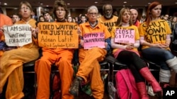 Activists from the antiwar group CodePink hold a silent protest aimed at the Senate Armed Services Committee during a hearing in Washington on the fate of the Guantanamo Bay detention center, Feb. 5, 2015.