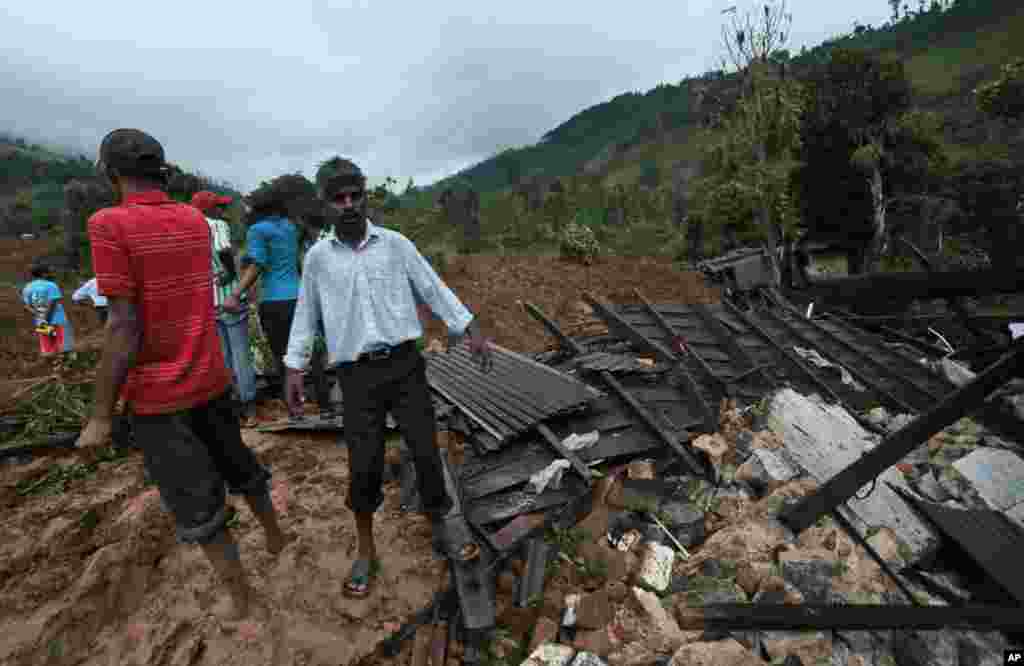 Sri Lankans stand at the site of a mudslide at the Koslanda tea plantation in the Badulla district, Sri Lanka, Oct. 29, 2014. 