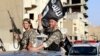 Militant Islamist fighters wave flags as they take part in a military parade along the streets of Syria's northern Raqqa province, June 30, 2014.