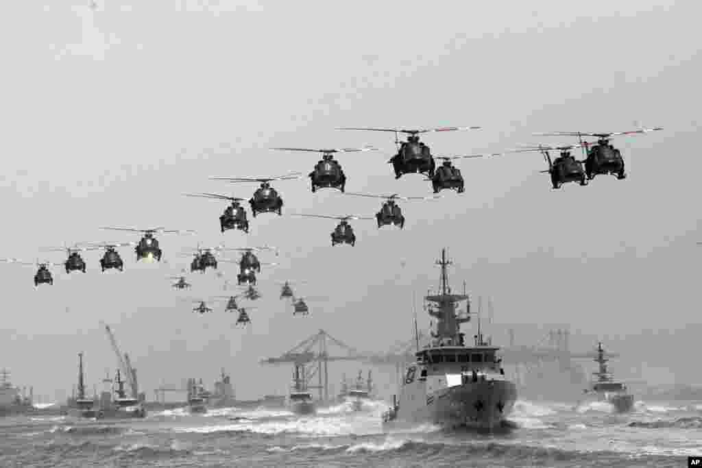 Indonesian Air Force helicopters fly in over the fleet of military ships in a show of force during a ceremony marking the 69th anniversary of Indonesian Armed Forces in Surabaya, East Java, Indonesia. 