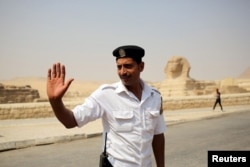 FILE - A policeman gestures to people as he stands guard near the Sphinx, near the pyramids plateau, Egypt, June 11, 2015.