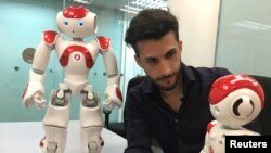 Lucas Apa, senior security consultant at cybersecurity company IOActive, handles robots by UBTech and SoftBank Robotics during a demonstration in Singapore, Aug. 21, 2017.