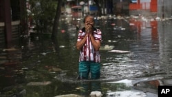 Seorang perempuan berjalan mengarungi air banjir di Jakarta, Indonesia, Sabtu, 4 Januari 2020. Hujan dan naiknya sungai merendam sebagian wilayah Jakarta dan menyebabkan tanah longsor di kabupaten Bogor dan Depok di pinggiran kota. Foto: AP)