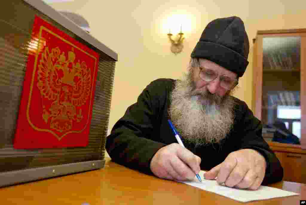 A monk fills in his ballot paper before voting during the presidential elections at the Nilova Pustyn monastery near the town of Ostashkov, some 350 km west of Moscow, March 4, 2012. (Reuters)