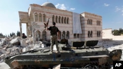 FILE - A Free Syrian Army soldier stands on a Syrian military tank in front of a mosque, which were damaged during fighting with government forces, in the Syrian town of Azaz, on the outskirts of Aleppo, Sept. 23, 2012.