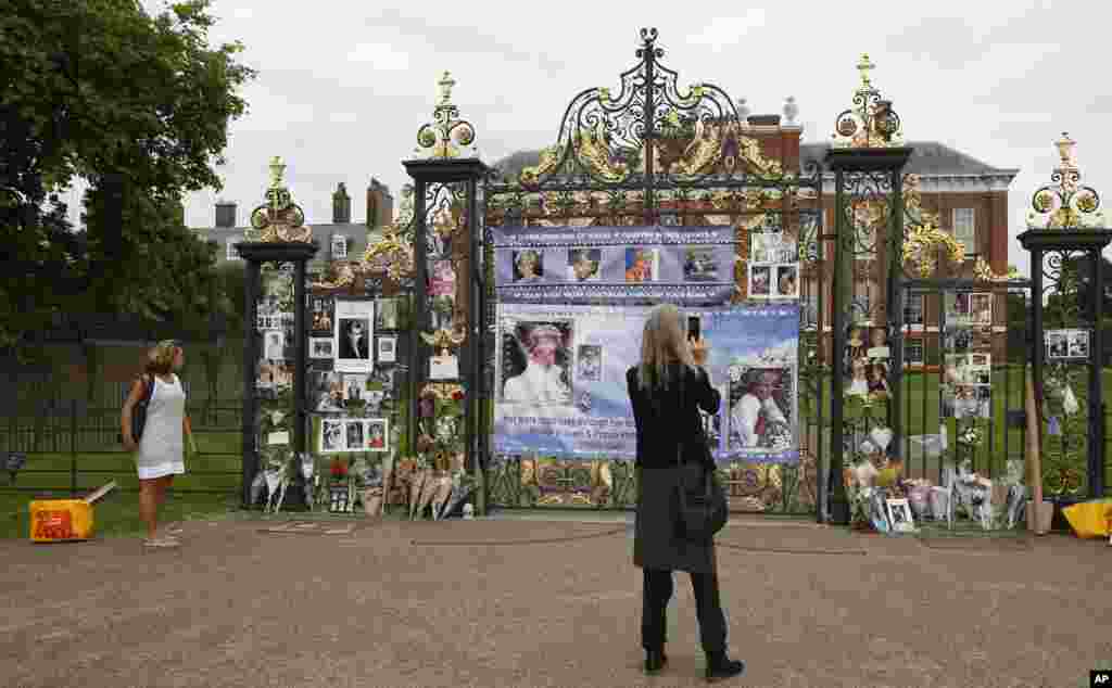 Tourists look at tributes and memorabilia for the late Diana, Princess of Wales outside Kensington Palace in London, Tuesday, Aug. 29, 2017. 