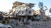 FILE - People walk past a building destroyed during recent fighting in Yemen's southwestern city of Taiz, March 14, 2016. 