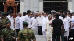 Sri Lankan President Maithripala Sirisena and Prime Minister Ranil Wickremasinghe, facing camera at right, attend a brief holy service marking the seventh day of the Easter attacks outside St. Anthony's Church in Colombo, Sri Lanka, April 28, 2019.