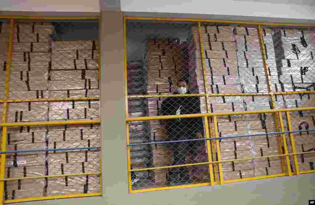 An electoral court worker stands next to election material at a distribution center in La Paz, Bolivia, which will hold general elections Oct. 18, 2020.