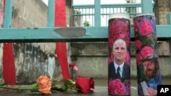 Votive candles bearing the photos of two men who were fatally stabbed on a Portland, Oregon, light-train while trying to stop another man from harassing two young women with an anti-Muslim tirade, sit on a rain-soaked memorial, May 30, 2107 in Portland. 