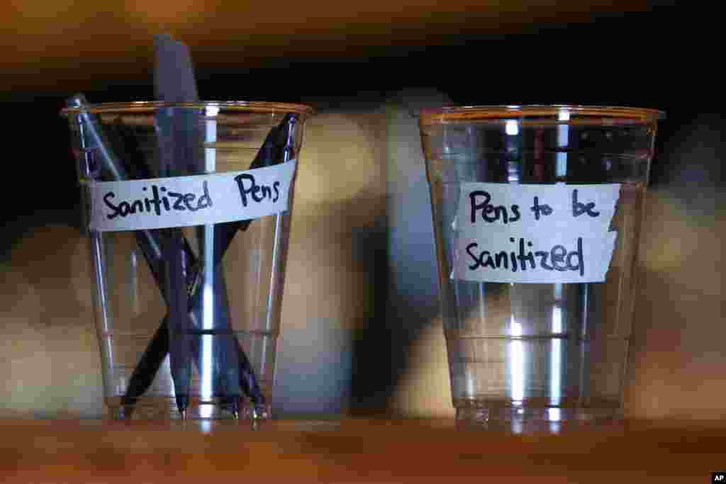 Sanitized pens are labeled in cups on the bar at O-Ku Sushi DC restaurant at Union Market in Washington, March, 17, 2020.