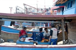 Para nelayan beristirahat di kapalnya di pelabuhan di Jakarta, 5 Mei 2019. (Foto: AFP)