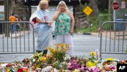 Women visit a memorial at 4th and Water Streets, Aug. 15 2017, in Charlottesville, Va., where Heather Heyer was killed when a car rammed into a group of counterprotesters last weekend. 