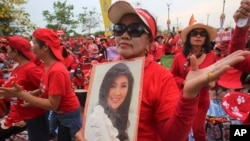A pro-government Red Shirt member dances with a portrait of Thai Prime Minister Yingluck Shinawatra during a rally in Bangkok, April 5, 2014. 