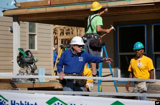 FILE - Former President Jimmy Carter helps cut wood for home construction at a Habitat for Humanity construction site in the Globeville neighborhood of Denver, Wednesday Oct. 9, 2013. (AP Photo/Brennan Linsley)