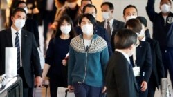 Mantan Puteri Jepang, Puteri Mako (kedua dari kiri) dan suaminya Kei Komuro (mengenakan sweater) mendapatkan pengawalan saat hendak masuk ke pesawat yang akan membawa mereka ke New York dari Bandara Internasional Tokyo, pada 14 November 2021. (AP/Eugene Hoshiko)