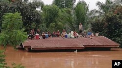 Villagers take refuge on a rooftop above flood waters from a collapsed dam in the Attapeu district of southeastern Laos, Tuesday, July 24, 2018. The official Lao news agency KPL reported Tuesday that the Xepian-Xe Nam Noy hydropower dam in Attapeu province collapsed Monday evening, releasing large amounts of water that swept away houses and made more than 6,600 people homeless. (Attapeu Today via AP) 