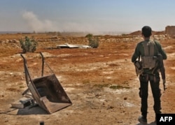 FILE - A Syrian rebel fighter watches smoke rising from an explosion, at an unknown location in Idlib province, Sept. 5, 2018.