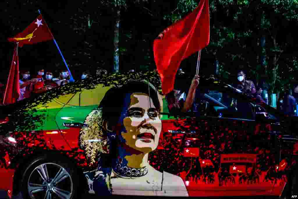 Supporters of the National League for Democracy (NLD) party wave flags outside the party's office in Mandalay, Myanmar, Nov. 8, 2020, as ballots for the parliamentary elections are being counted after the polls closed.