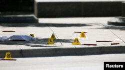 FILE - Markers litter the sidewalk as FBI investigators look over a crime scene in Dallas, Texas, July 8, 2016.