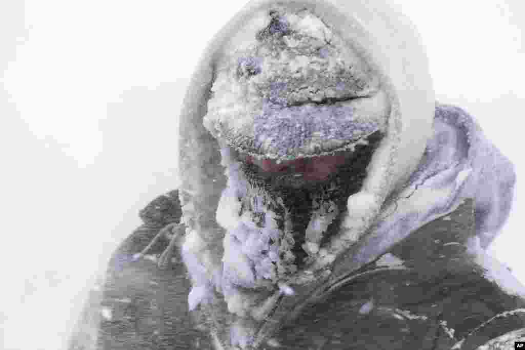 Daniel Davis is covered in snow and ice while clearing a sidewalk during a snowstorm in Detroit, Michigan, USA, Mar. 12, 2014.