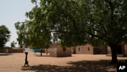 FILE - A girl carries a bucket of water from a community well in Ndiawagne Fall village in Kebemer, Senegal, Nov. 5, 2021. The region is on one end of a project called the Great Green Wall that was once envisioned as a way for Africa to fight climate change.