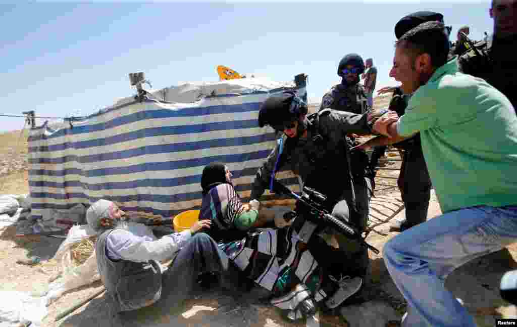 Palestinians scuffle with an Israeli border policeman as Israeli troops demolish sheds belonging to Palestinians near the West Bank village of Yatta, south of Hebron.