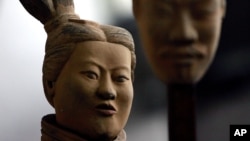 FILE - A female terracotta soldier statue holds the mask of a man as it stands in an army made up of women and children at an art gallery in Beijing, Feb. 24, 2007. Women in China say they are seeing an eroding of their status from the days of Mao Zedong
