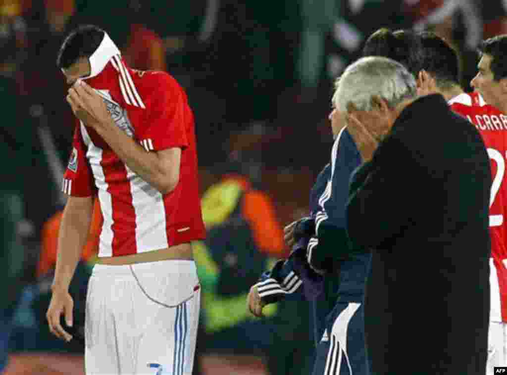 Paraguay's Oscar Cardozo, left, covers his face with his jersey at the end of the World Cup quarterfinal soccer match between Paraguay and Spain at Ellis Park Stadium in Johannesburg, South Africa, Saturday, July 3, 2010. Spain won 1-0 and Cardozo missed 