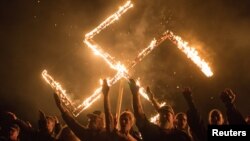 Arhiv - Pristalice nacionalsocijalističkog pokreta, političke grupe bijelih nacionalista, u stavu nacističkog pozdrava dok učestvuju u paljenju svastike na nepoznatoj lokaciji u Georgiji, SAD.