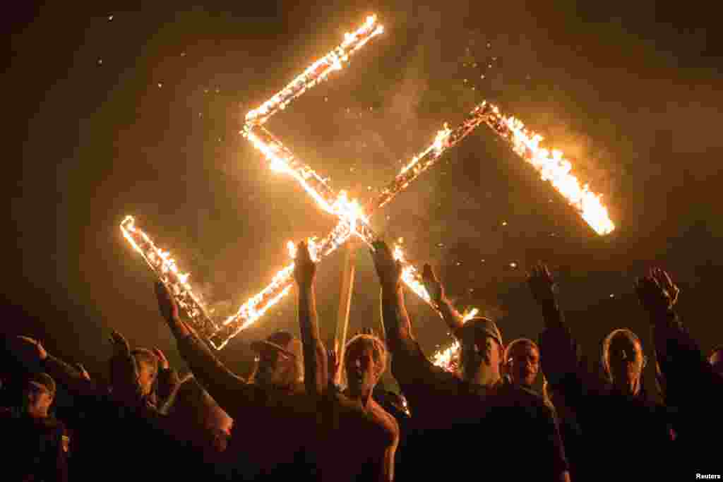 Supporters of the National Socialist Movement, a white nationalist political group, give Nazi salutes while taking part in a swastika burning at an undisclosed location in Georgia, U.S.