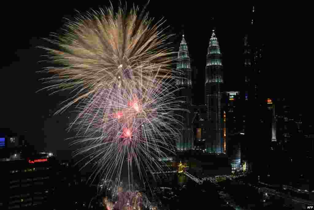 煙花在馬來西亞首都吉隆坡的雙子塔上空綻放，迎接2018年1月1日新年的到來。