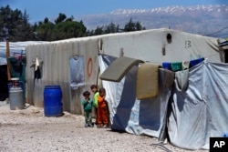 Syrian refugee children stand next to their family tents at a Syrian refugee camp in the town of Bar Elias, in Lebanon's Bekaa Valley, April 23, 2018.