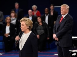 Democratic presidential nominee Hillary Clinton, left, talks as Republican presidential nominee Donald Trump watches her during the second presidential debate at Washington University in St. Louis, Sunday, Oct. 9, 2016.