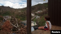 A boy looks at his neighbourhood after Hurricane Maria destroyed the town's bridge and the surrounding areas, in San Lorenzo, Morovis, Puerto Rico, Oct. 5, 2017. 