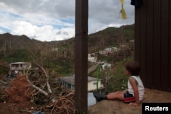 A boy looks at his neighbourhood after Hurricane Maria destroyed the town's bridge and the surrounding areas, in San Lorenzo, Morovis, Puerto Rico, Oct. 5, 2017.