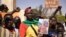 Des manifestants rassemblés à Ouagadougou pour montrer leur soutien aux militaires tiennent une photo du lieutenant-colonel Paul-Henri Sandaogo Damiba, chef de la mutinerie et du Mouvement patriotique pour la protection et la restauration (MPSR) le 25 janvier 2022.