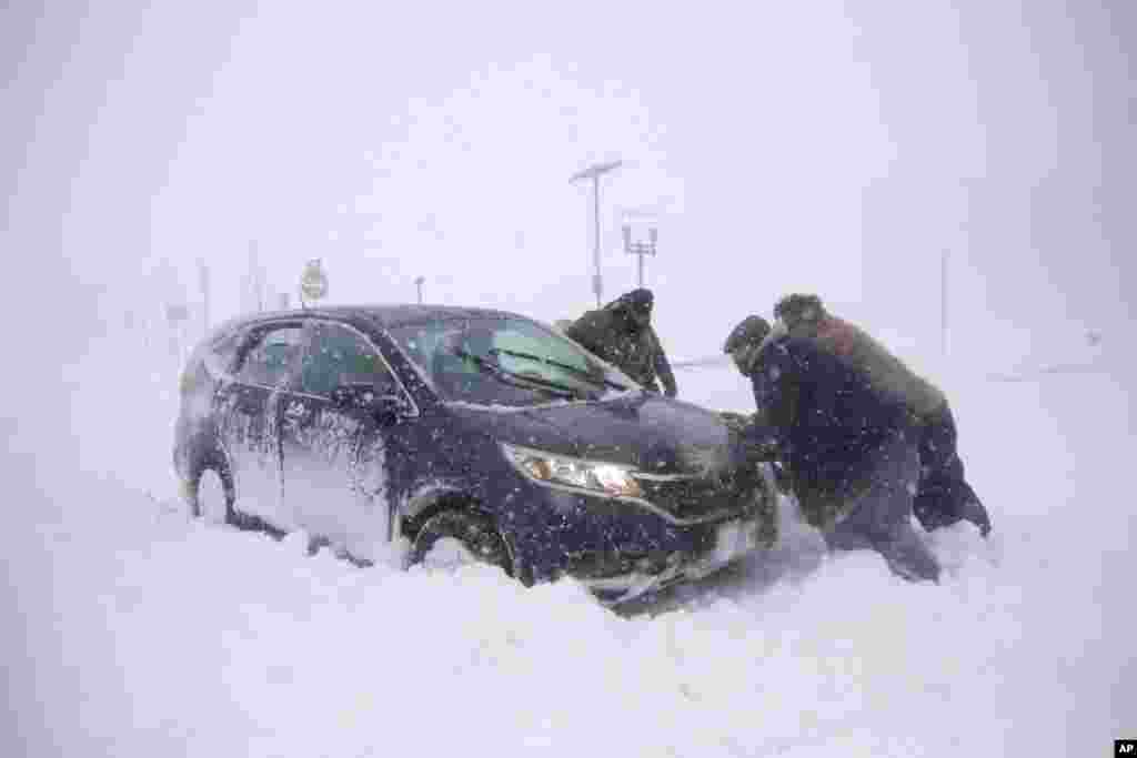 A group of men help a motorist after his vehicle was stuck in the snow near Asbury Park boardwalk during a snowstorm in Asbury Park, New Jersey.