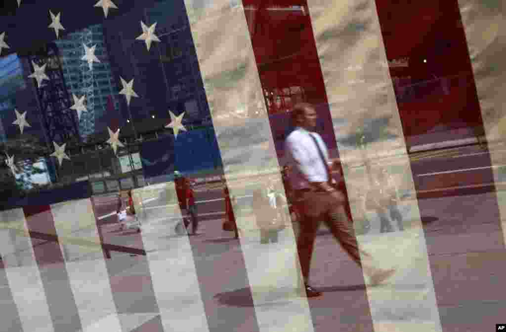 A man is reflected in a window draped with a U.S. flag across from the World Trade Center construction site in New York.
