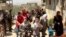 This photo, released by the Syrian official news agency SANA, shows civilians carrying their belongings leaving towns and villages, in the eastern Ghouta region near Damascus, Syria, March. 25, 2018. 