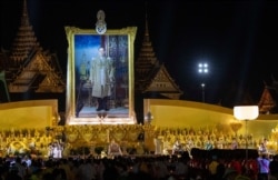 Thai King Maha Vajiralongkorn and members of the royal family sit in front of a portrait of the late King Bhumibol Adulyadej during a ceremony to mark the late king's birthday, at Sanam Luang ceremonial ground in Bangkok, Thailand, Dec. 5, 2020.