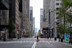 A man walks dogs across a nearly empty 5th Avenue and closed luxury retail stores, during the outbreak of the coronavirus disease (COVID-19), in Manhattan, New York City, New York, May 11, 2020.