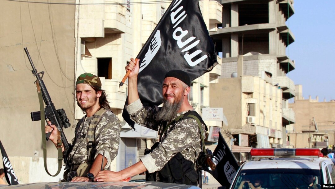 Militant Islamist fighters wave flags as they take part in a military parade along the streets of Syria's northern Raqqa province, June 30, 2014.