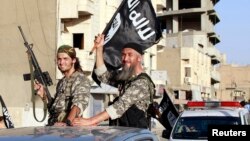 Militant Islamist fighters wave flags as they take part in a military parade along the streets of Syria's northern Raqqa province, June 30, 2014.